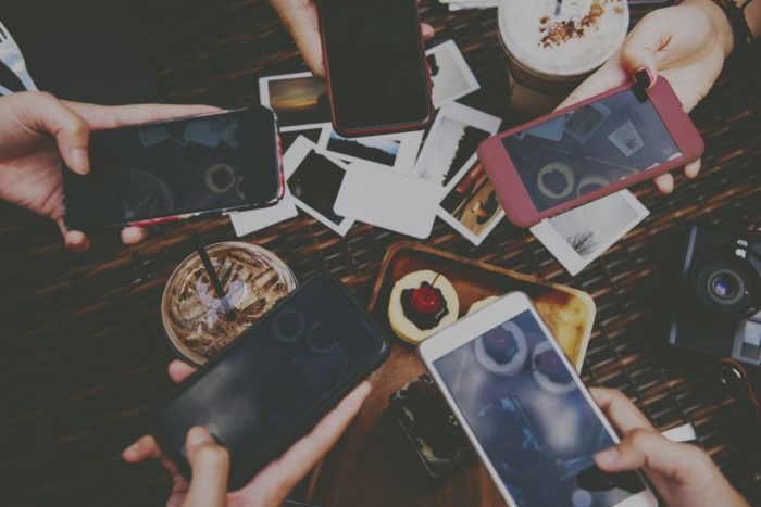 People taking photos with their smartphones as part of a virtual escape room game.